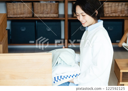 Young woman tidying up clothes Young woman tidying up clothes 122592125