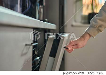 Hand opening dishwasher door in modern kitchen 122592372
