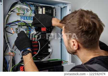 Electrician Repairing Heat Pump Control Panel 122592474