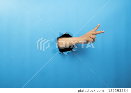 Human hand showing from ripped paper. Hand gestures of greeting or counting. Mockup or Copy space. Concept of sign or communication 122593284