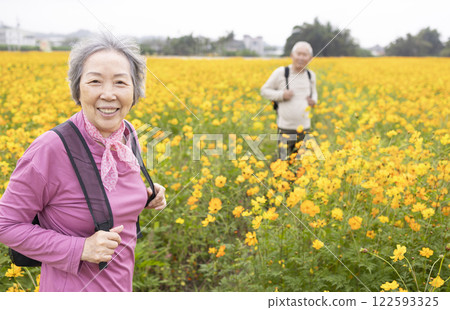 Happy senior couple hiking on trail by flowers plants at spring Happy senior couple hiking on trail by flowers plants at spring 122593325