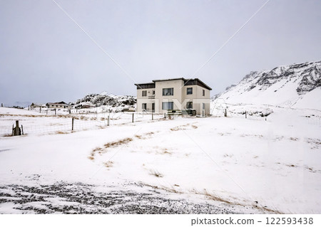 View of house with snow covered fields and mountains in Iceland. Nature, travel, winter background, or wallpaper View of house with snow covered fields and mountains in Iceland. Nature, travel, winter background, or wallpaper 122593438