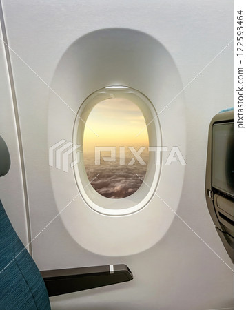 View through the airplane window of cloudscape with sunlight during a flight in the sky. Nature, horizon, travel background, or wallpaper View through the airplane window of cloudscape with sunlight during a flight in the sky. Nature, horizon, travel background, or wallpaper 122593464