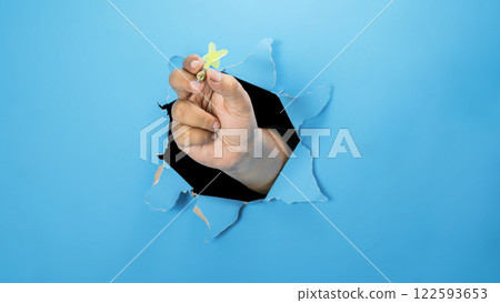 A human hand holding a dart arrow through ripped paper. Mockup or Copy space. Concept of target and challenge 122593653