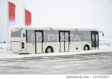 Tourist bus drove through snow capped streets with winter scenery in Iceland. Transportation, travel, industry, service, winter background, or wallpaper 122593857