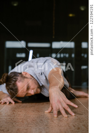 A man performs a randomized movement for yoga at a fitness gym 122594191