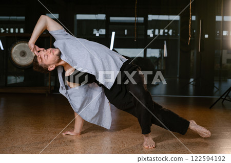 A man performs a randomized movement for yoga at a fitness gym 122594192