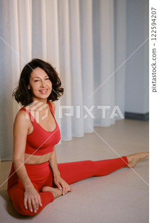 A woman in a red tracksuit sits on the floor of a fitness room. Kalimeditation class A woman in a red tracksuit sits on the floor of a fitness room. Kalimeditation class 122594207