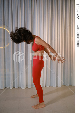 A woman in red sportswear does dynamic meditation cali at a fitness gym A woman in red sportswear does dynamic meditation cali at a fitness gym 122594221
