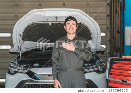 Middle-aged Asian man, mechanic, auto mechanic working at a repair shop Middle-aged Asian man, mechanic, auto mechanic working at a repair shop 122594525