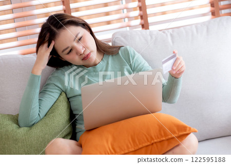 Young asian woman holding credit card or debit card with stress about loan and expense. 122595188