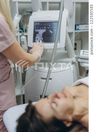 Professional cosmetologist performing LPG facial skin massage for rejuvenation in beauty salon. 122595585