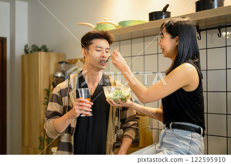 Happy young couple sharing a healthy salad in the kitchen 122595910