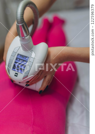 Lpg massage procedure. Hands of therapist holding lipomassage tool. Close up, selective focus. 122596379