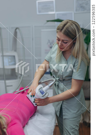 Lpg massage procedure. Hands of therapist holding lipomassage tool. Close up, selective focus. 122596385