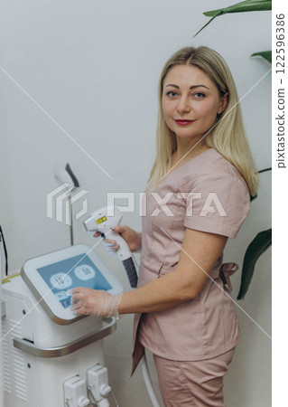 young woman master of laser hair removal, laser apart, woman smiles,Cosmetology section hair removal young woman master of laser hair removal, laser apart, woman smiles,Cosmetology section hair removal 122596386