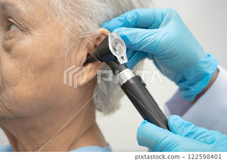 Otolaryngologist or ENT physician doctor examining senior patient ear with otoscope, hearing loss problem. Otolaryngologist or ENT physician doctor examining senior patient ear with otoscope, hearing loss problem. 122598401