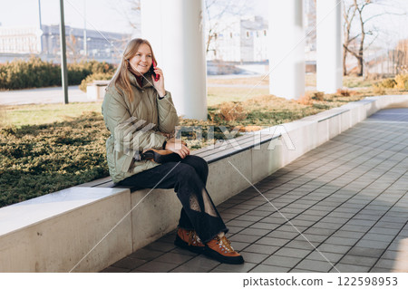 Happy 30s woman talking phone and look happy outdoors. Urban lifestyle concept. Spring time. Beautiful woman walking on the modern city street. 122598953