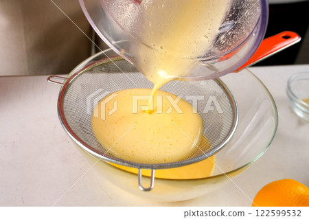 Pastry chef cooking tangerine pie filtering orange cream filling through sieve. 122599532