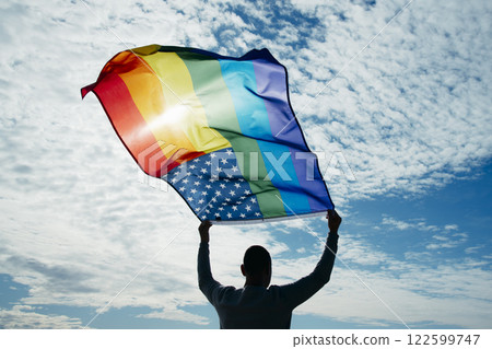 LGBTIQ person waving a rainbow US flag on the sky 122599747