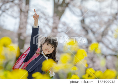一名一年級的小學生在種滿油菜花和櫻花的公園散步 122599938