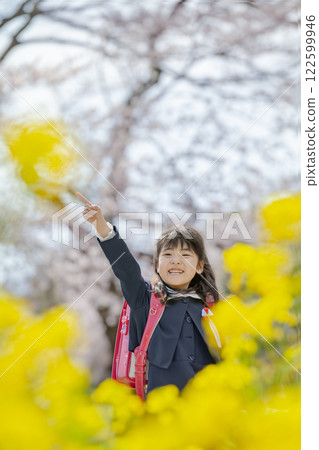 一名一年級的小學生在種滿油菜花和櫻花的公園散步 122599946