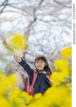 一名一年級的小學生在種滿油菜花和櫻花的公園散步 122599947