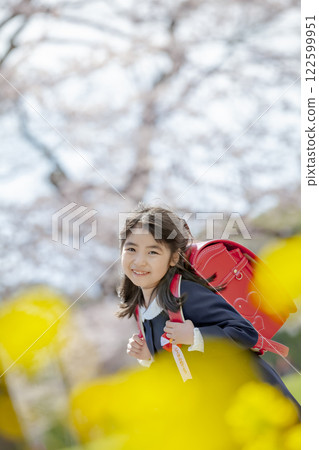 一名一年級的小學生在種滿油菜花和櫻花的公園散步 122599951
