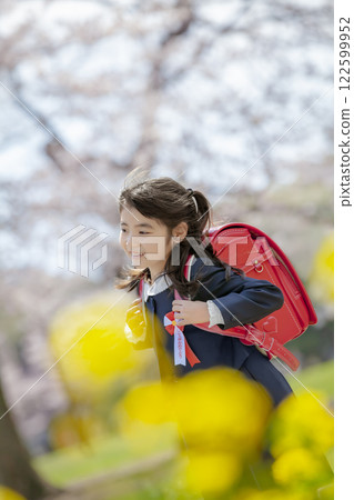 一名一年級的小學生在種滿油菜花和櫻花的公園散步 122599952