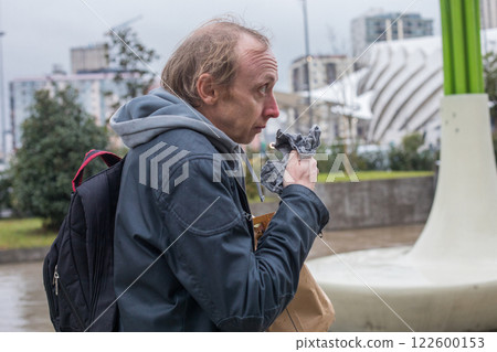A Man with Flu is Walking in Public Park and Sneezing in Tissues Outdoors 122600153