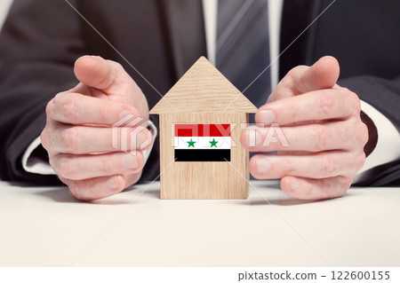 Businessman hand holding wooden home model with Syrian flag. insurance and property concepts 122600155