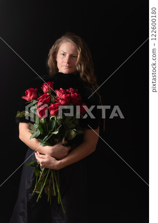 Beautiful young woman with bouquet of red roses flowers on black studio background Beautiful young woman with bouquet of red roses flowers on black studio background 122600180