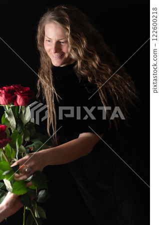 Beautiful young woman with bouquet of red roses flowers on black studio background 122600218