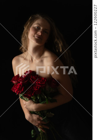 Sensual beautiful woman with bare shoulders and red roses on a dark studio background 122600227