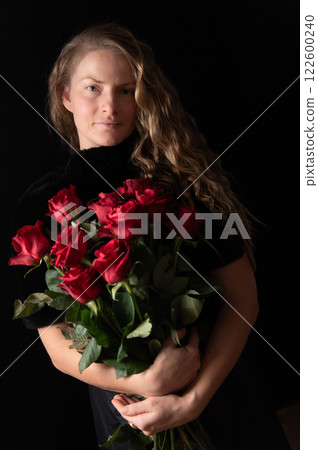 Beautiful young woman with bouquet of red roses flowers on black studio background 122600240
