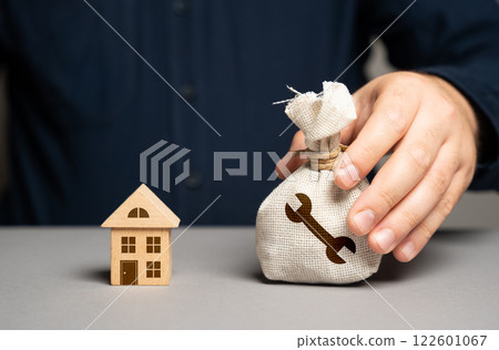 A man with a money bag containing funds for home renovation. Budgeting, and financial planning. Home improvement, and repairs. Boost property value. Make better living conditions. 122601067