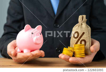 A businessman holds a piggy bank and a money bag with interest. Savings or deposit. Compare profitability and risks. Investment prospects. 122601091
