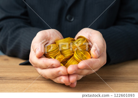 Businessman holding a handful of gold coins. Wealth and capital. High salary. Income and bonuses. High margin. 122601093