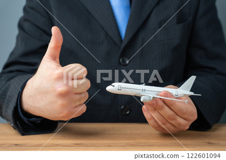 A man in a suit holds an airline plane and gives a thumbs up gesture. Permission to fly. Great deals on flight tickets. Loyalty program and bonus air lines. 122601094