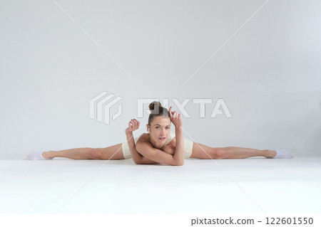A flexible woman performs a full split while resting on the floor, maintaining a calm and confident expression. The increasing focus on body mobility and flexibility highlights the importance of A flexible woman performs a full split while resting on the floor, maintaining a calm and confident expression. The increasing focus on body mobility and flexibility highlights the importance of 122601550