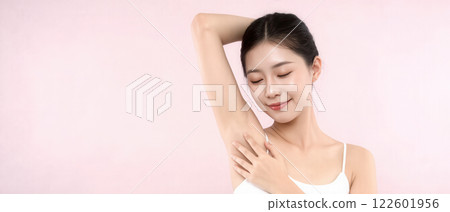 Beautiful Korean woman with flawless underarm skin posing confidently in a soft pink background 122601956