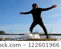 Playful man breaks a block of ice near frozen river on nature in sunny day. 122601966