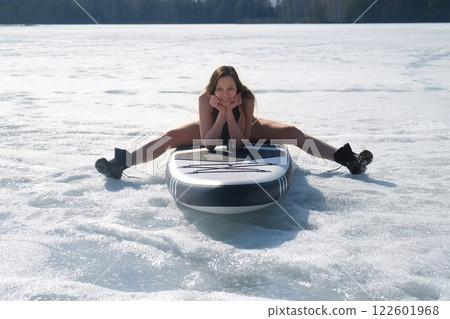 Happy brunette woman in swimsuit sitting on sup board posing looking at camera. 122601968