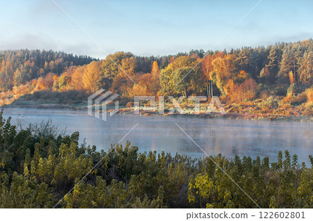 Colorful autumn tree forest behind the river, landscape with fog over the water 122602801
