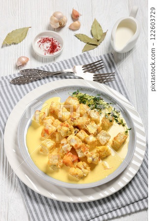 pollock cubes poached in cream saffron sauce 122603729