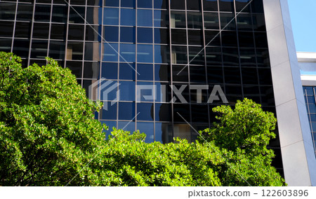 Eco-friendly building in the modern city. Sustainable glass office building with trees for reducing heat and carbon dioxide. Office building with green environment. Corporate building reduce 122603896