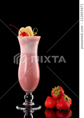 Glass of fresh strawberry milkshake decorated with cocktail cherry and banana slices isolated at black background. 122603971