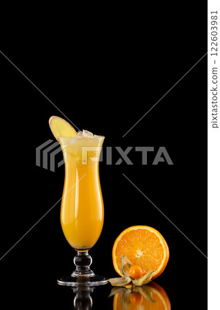 Closeup glass of fresh orange juice with ice decorated with ginger isolated at black background. Closeup glass of fresh orange juice with ice decorated with ginger isolated at black background. 122603981