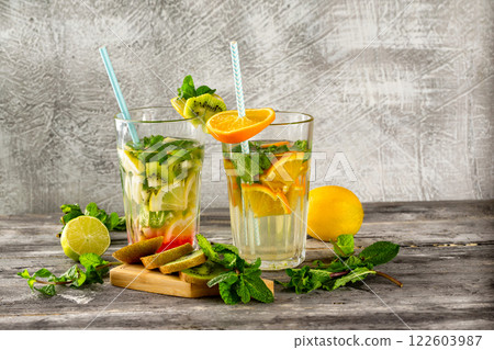 Two glasses of detox water with lemon, kiwi, orange and mint at concrete decorated table background. Concept of healthy lifestyle. 122603987