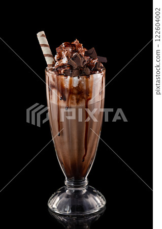 Closeup glass of chocolate milkshake decorated with caramel and whipped cream isolated at black background. 122604002